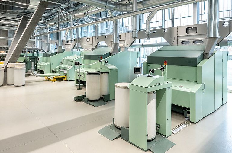 Interior view of the Spin Center at the Rieter Innovation Center in Winterthur, Switzerland. In the foreground, a Rieter expert checks the settings of a card.