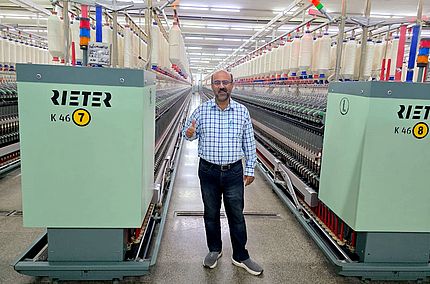 Masood Fabrics Limited Teknik Direktörü Malik Asad Ullah (Eğirme Pozisyonu) Rieter kompakt iplik eğirme K 46 makinesinin önünde duruyor