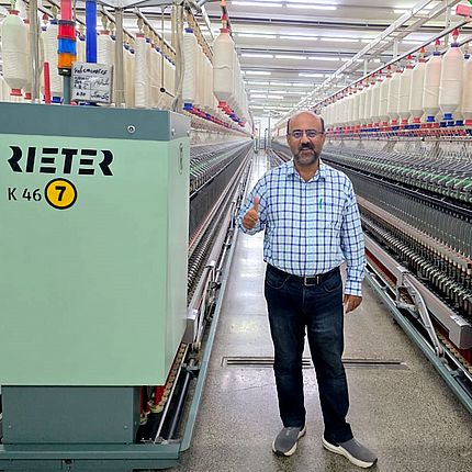 Masood Fabrics Limited Teknik Direktörü Malik Asad Ullah (Eğirme Pozisyonu) Rieter kompakt iplik eğirme K 46 makinesinin önünde duruyor