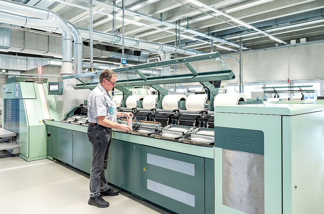 Interior view of the Spin Center at the Rieter Innovation Center in Winterthur, Switzerland. In the foreground, a Rieter expert works on a comber.