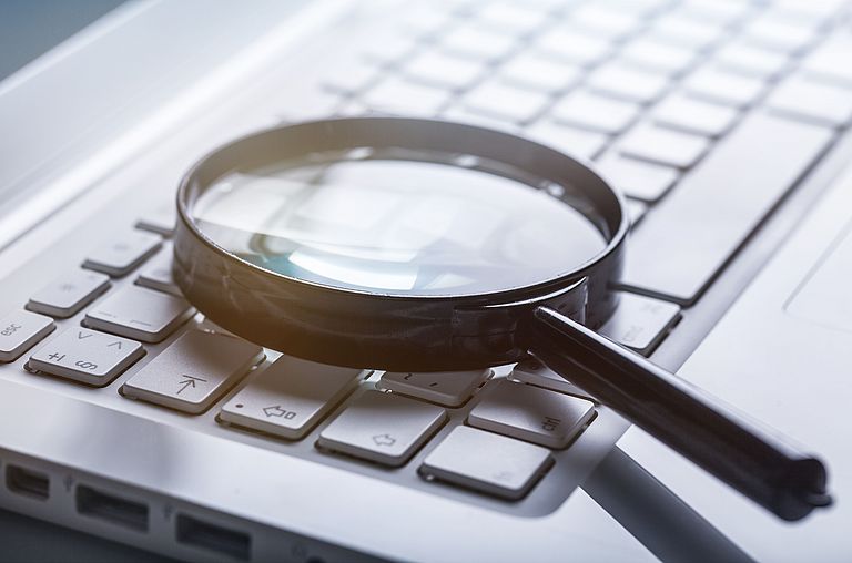 Magnifier glass on a computer keyboard: Digitalization facilitates fault detection.