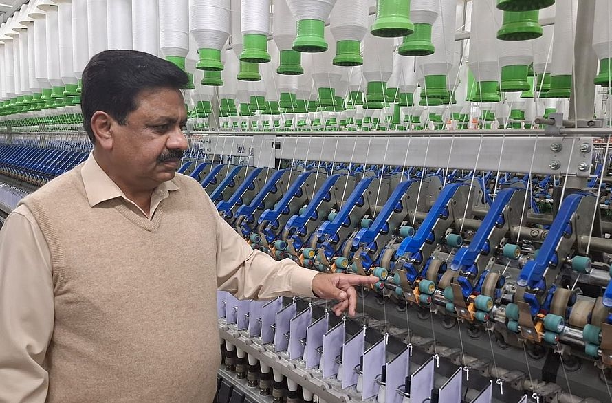 Tariq Nazir站在Ibrahim Fibres Limited的紧密纺纱机前面。