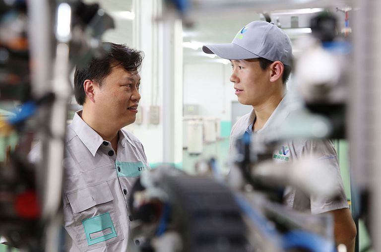 Close-up of a Rieter and a spinning mill employee standing in a spinning mill