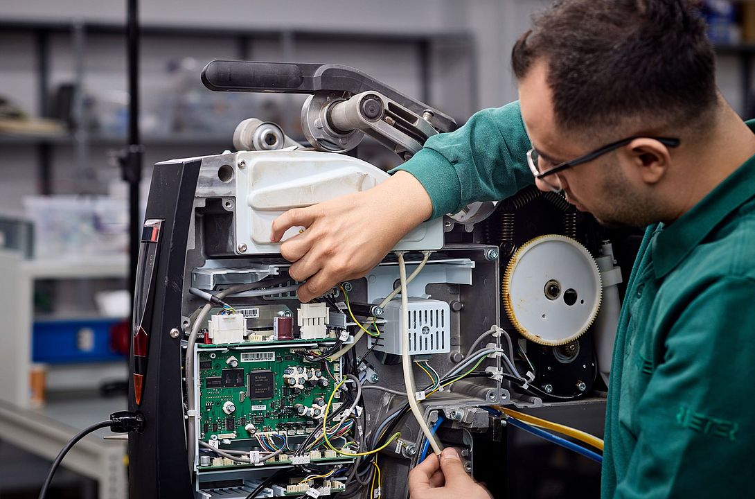 Rieter service expert performing electrical repair on the winding machine