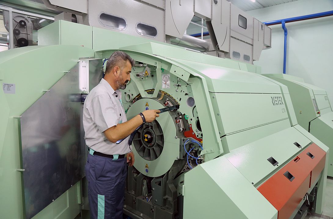 Rieter field service expert is working on the carding machine and checking the critical settings with the tool